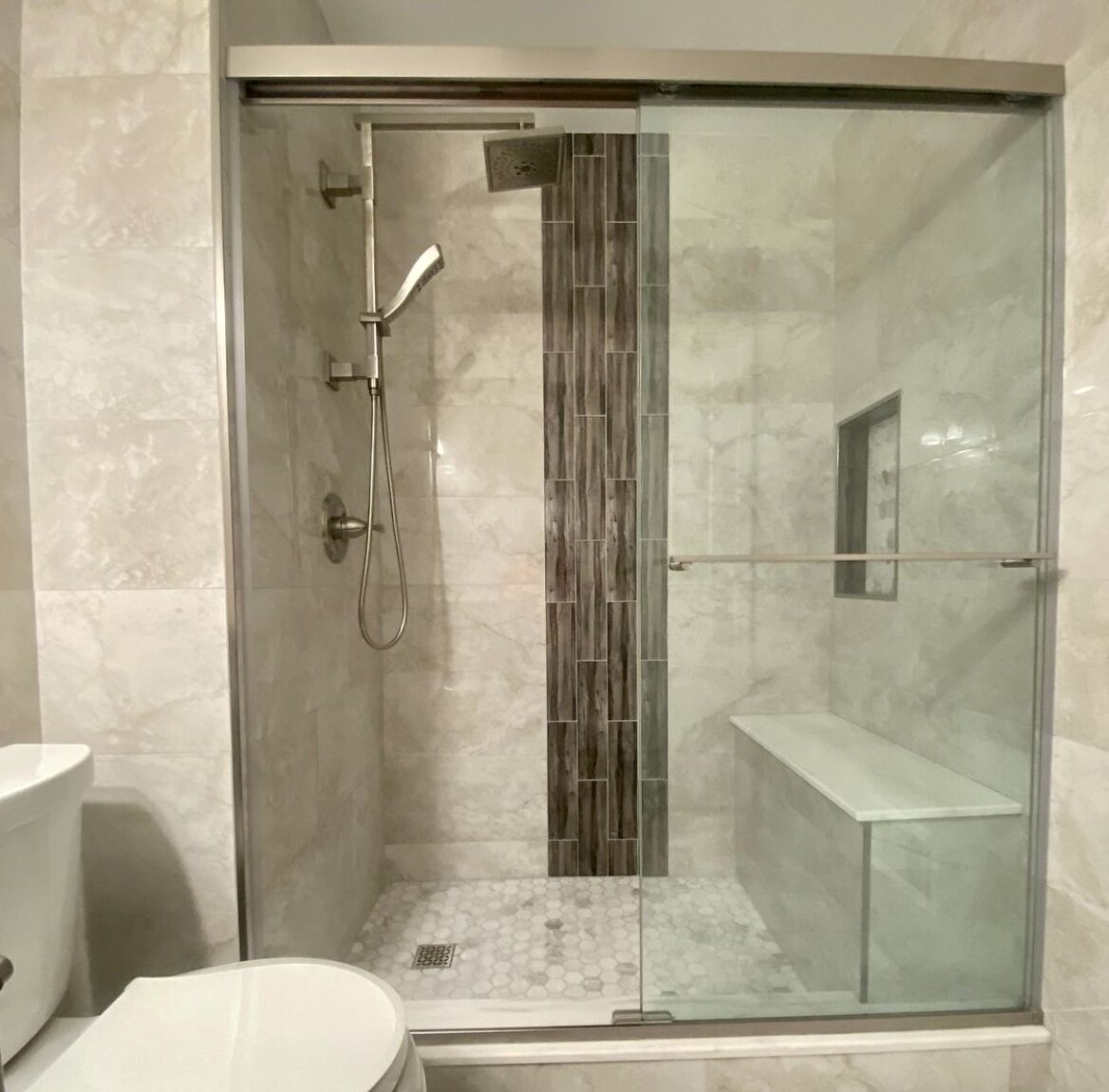 Large tiled walk-in shower with bench